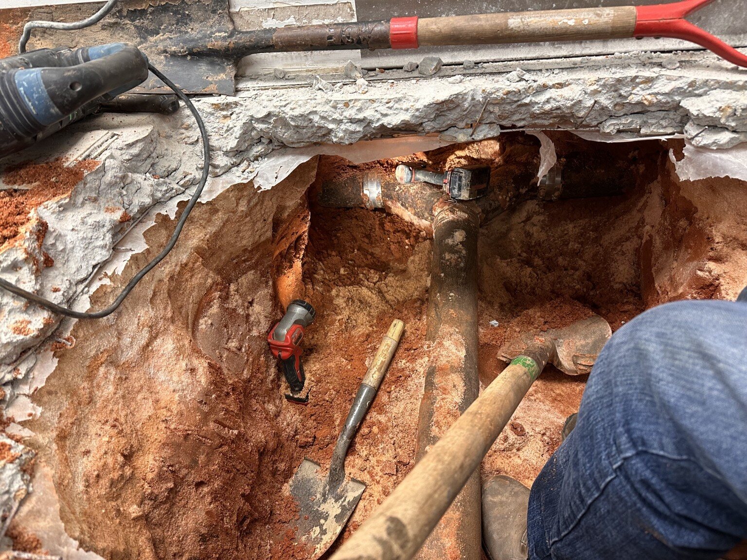 Underground drain line exposed below the concrete floor