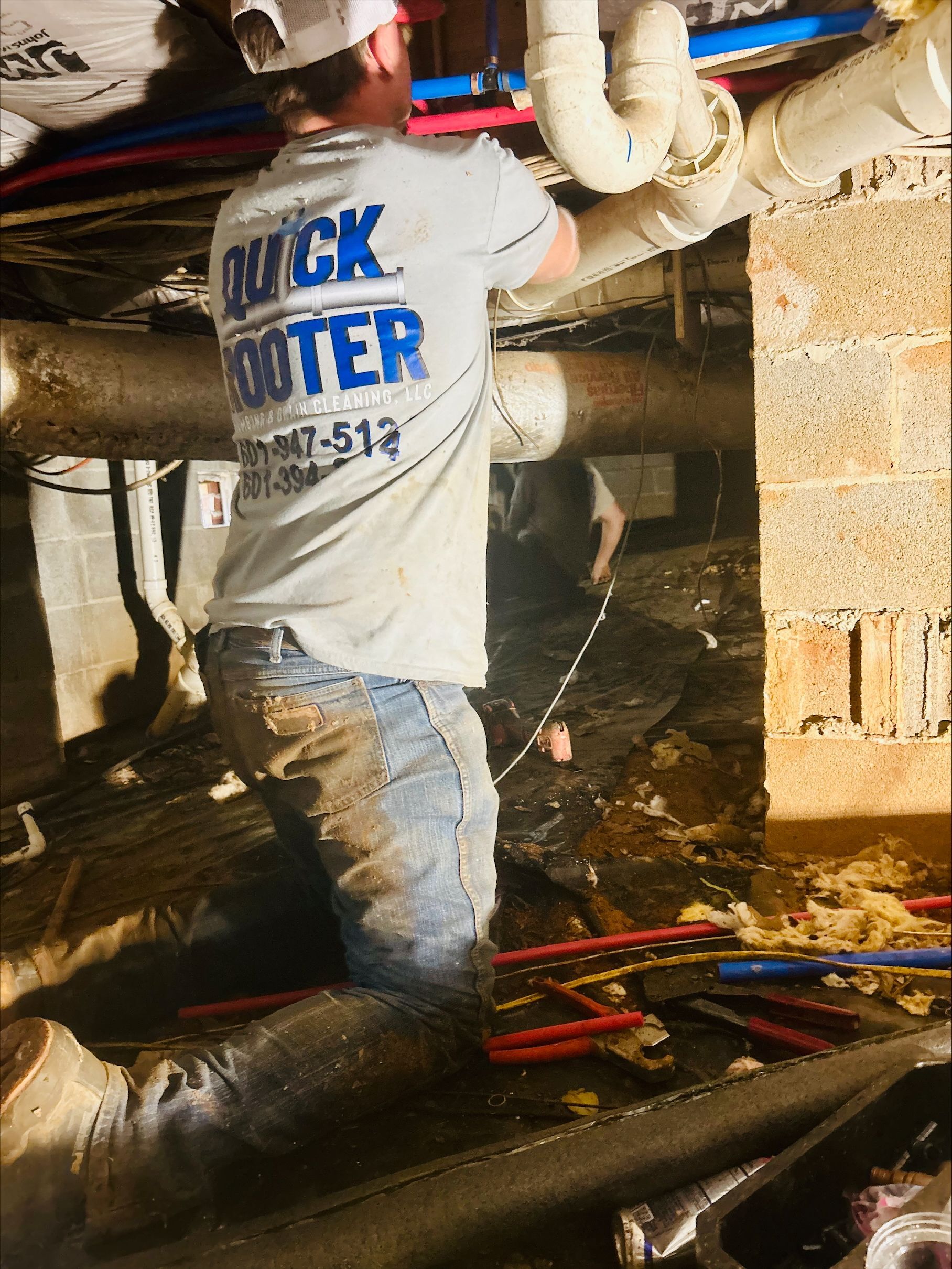 Quick Rooter plumber completing piping work beneath a building